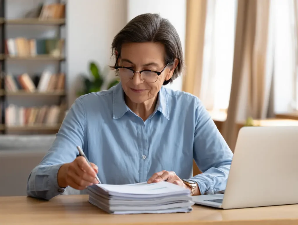 A supportive, realistic illustration of an adult reviewing health insurance paperwork at home, laptop on table, calm and hopeful mood, professional healthcare theme, natural lighting, no text, no logos, high resolution